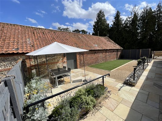 Warm sunny afternoon in the garden. White gazebo with table and chairs under it. The ground has paving.